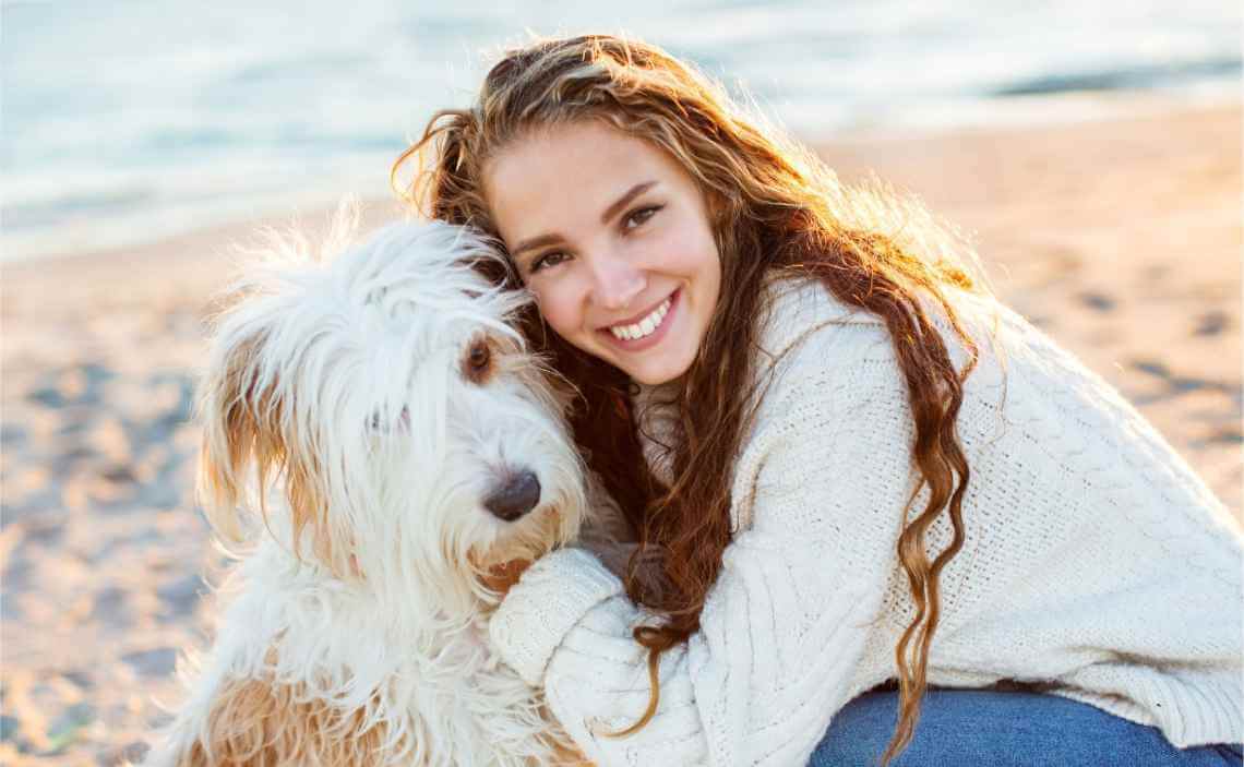 FLUFFY DOG WITH WOMAN AT BEACH