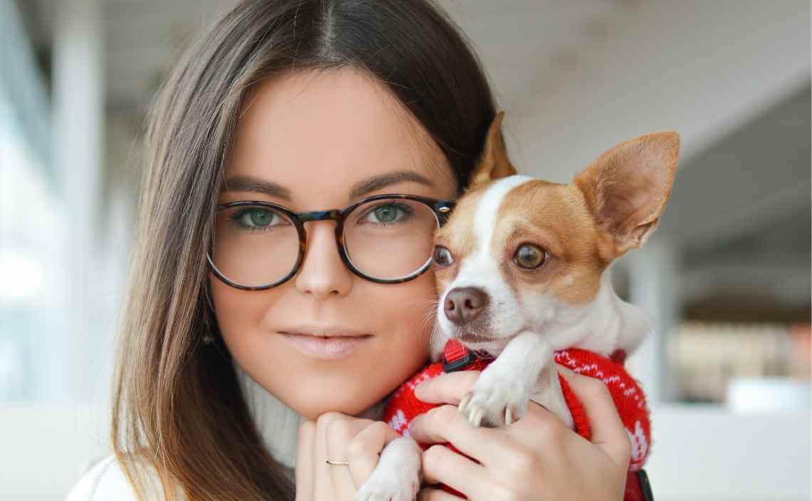 WOMAN HOLDING SMALL DOG WITH RED SWEATER