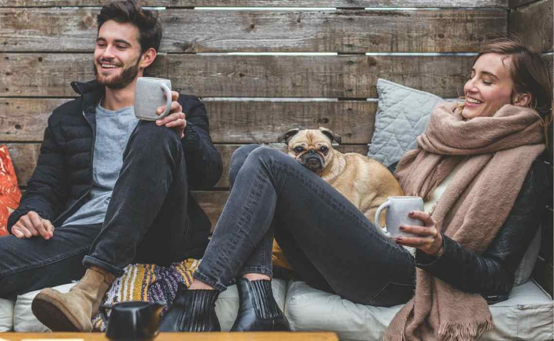 YOUNG COUPLE WITH DOG HOLDING COFFEE CUPS
