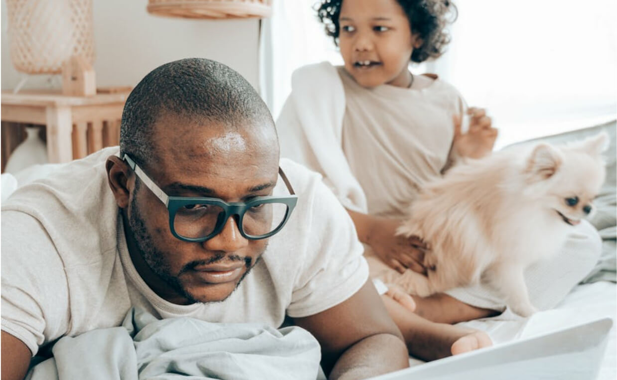 man trying to work with daughter and dog in background