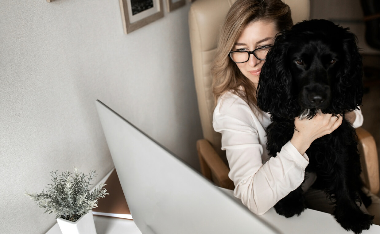 woman working from home holding black fluffy dog on lap