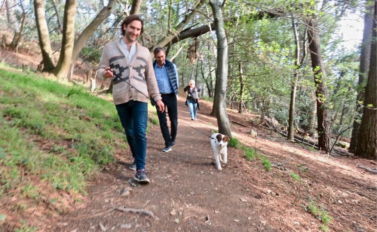 man hiking with white and brown dog on leash