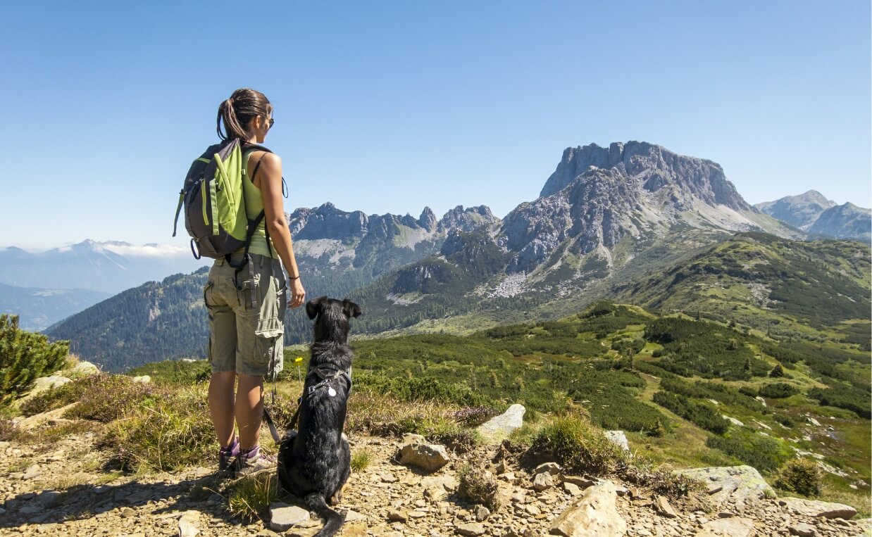 IS HIKING GOOD FOR DOGS - woman hiking with dog in summer