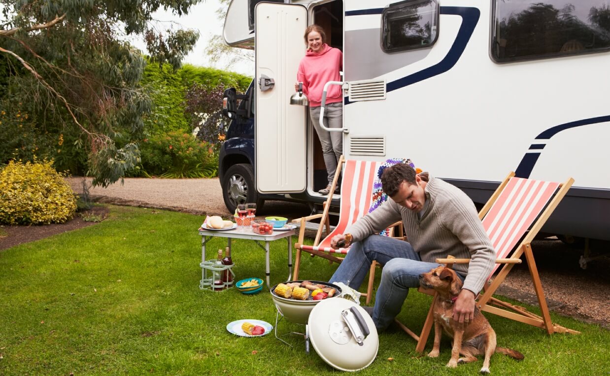 RV PET TEMPERATURE MONITOR FAMILY CAMPING IN RV HAVING DINNER OUTSIDE MAN PETTING DOG