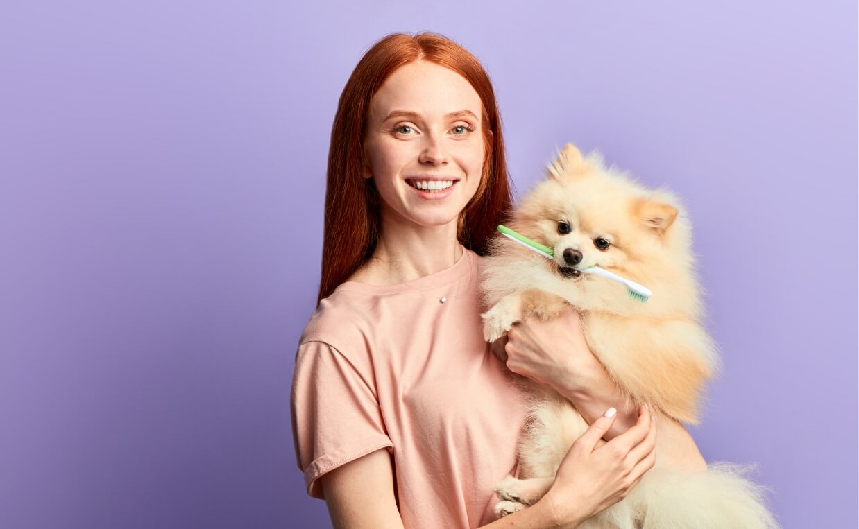 HAPPY WOMAN WITH DOG WITH TOOTHBRUSH IN MOUTH