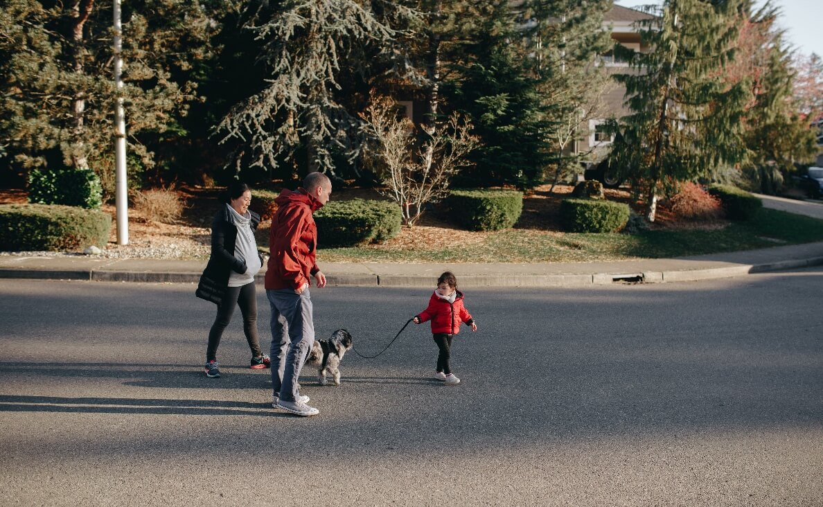 when can kids help with the family dog - family walking the dog with toddler holding the leash
