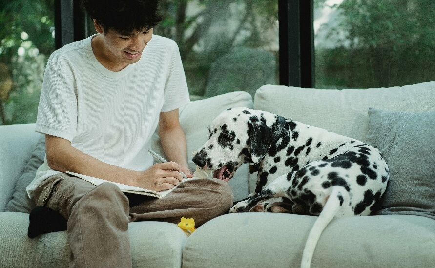 The Unexpected Benefits of a Dog Journal - young man writing with dalmation next to him